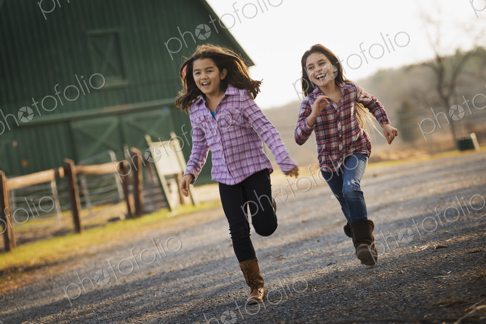 Two children running along a road, by a farm building, on an organic farm.