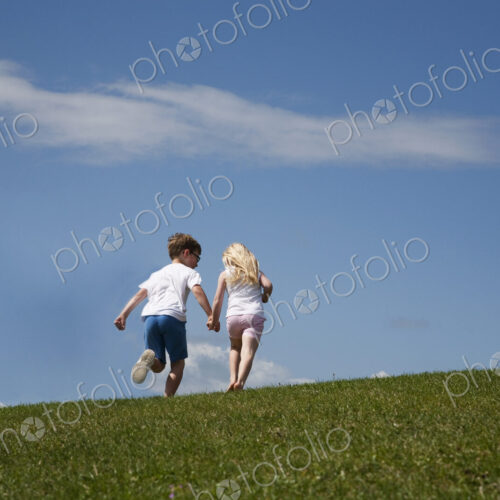 Two children running up a hill Two children running up a hill