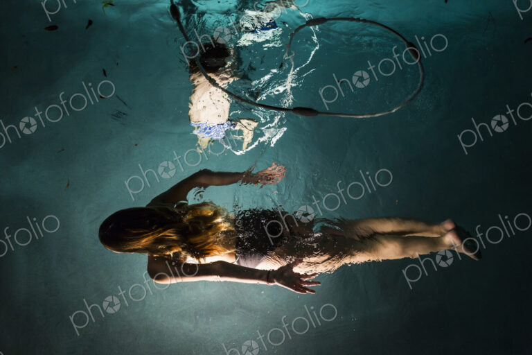 Two children swimming in pool at night