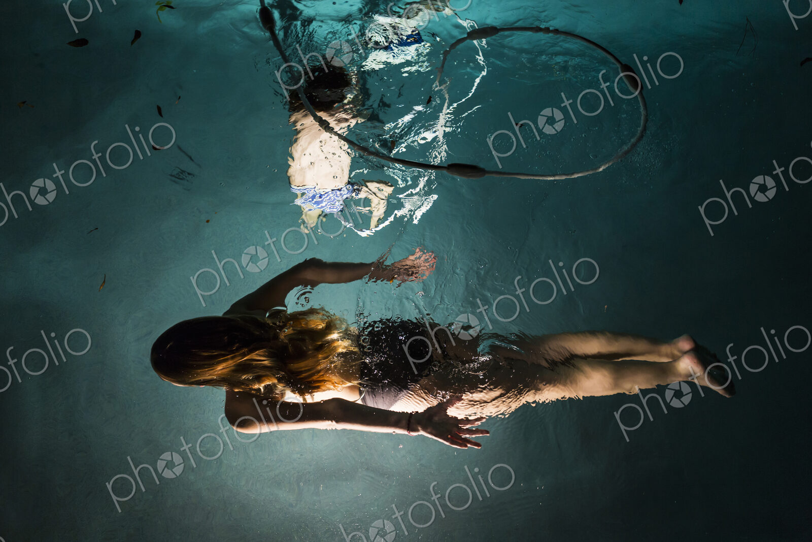 Two children swimming in pool at night