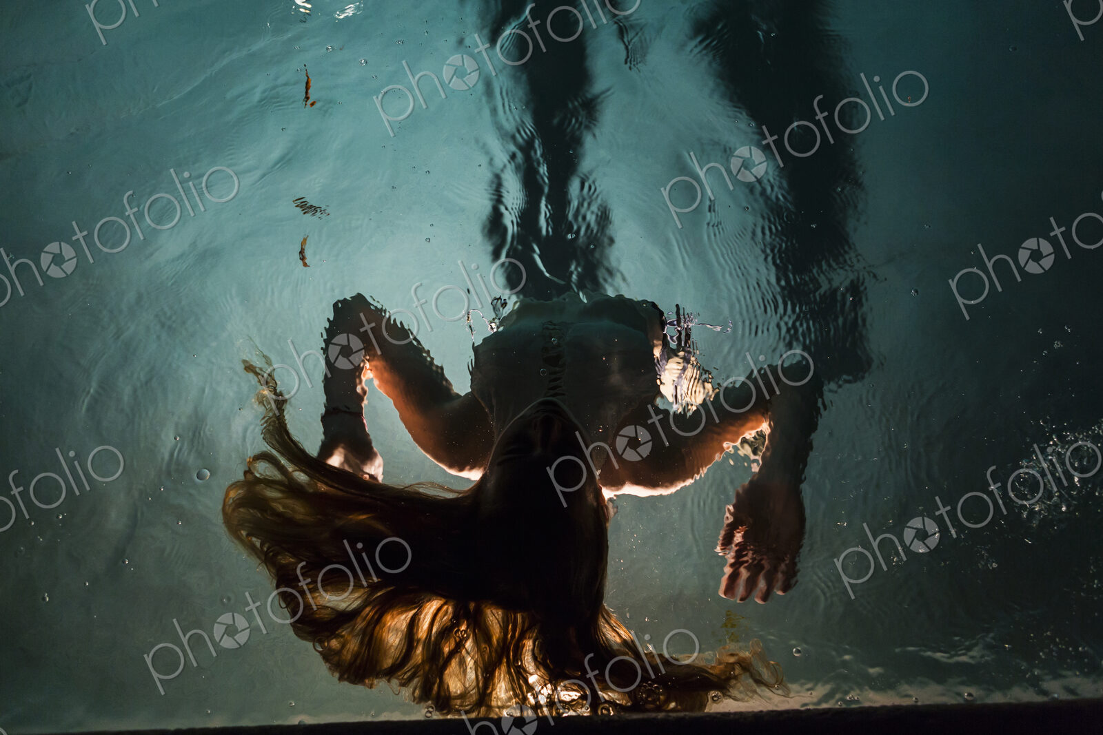 Two children swimming in pool at night