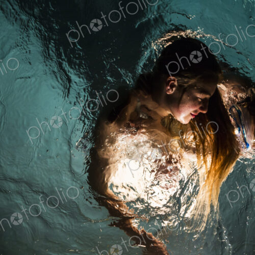 Two children swimming in pool at night Two children swimming in pool at night