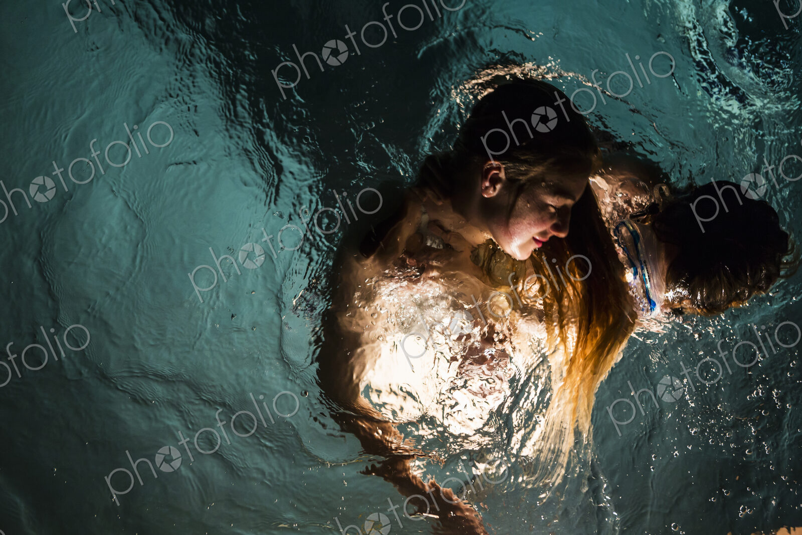 Two children swimming in pool at night