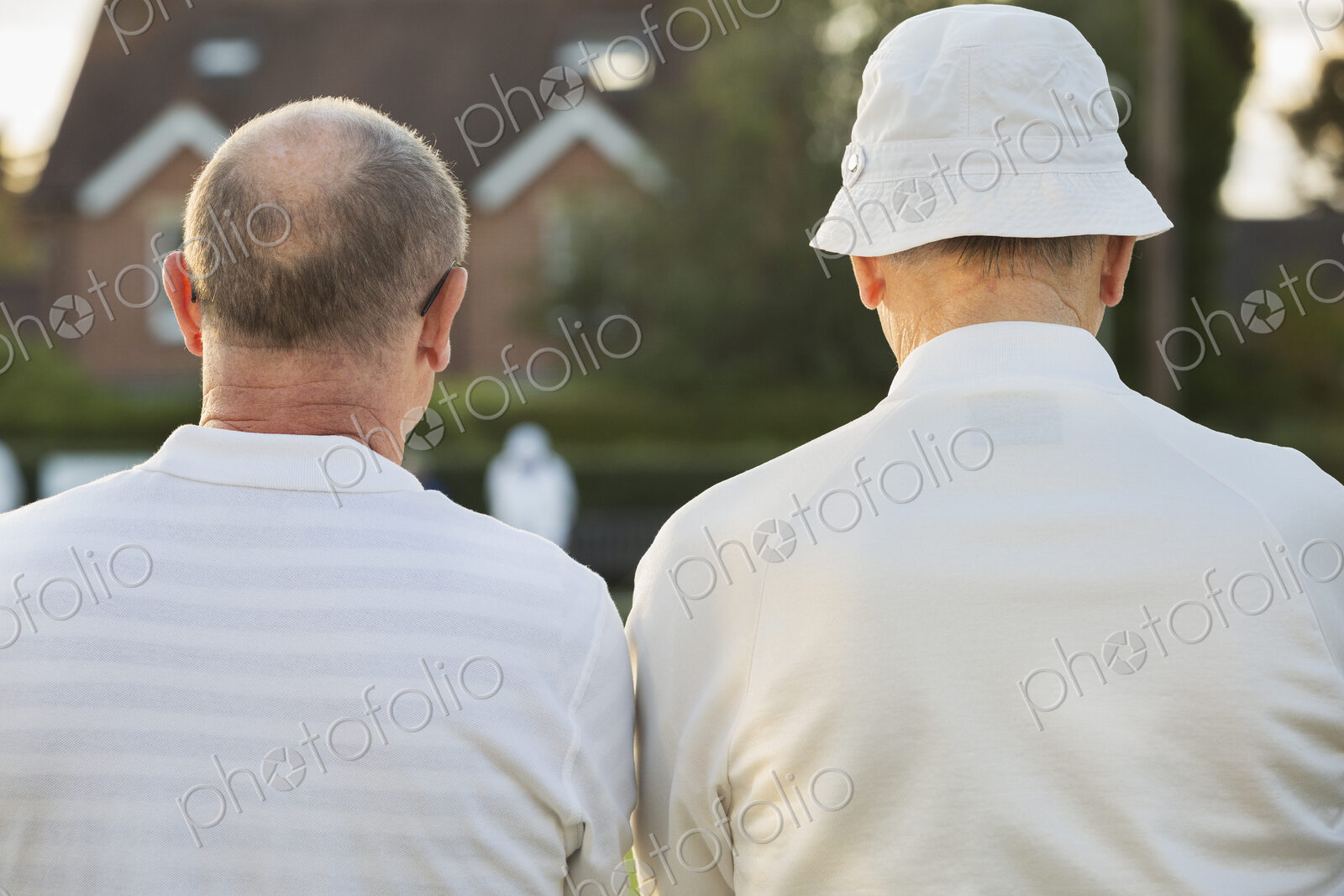Two companions, two men standing side by side in white shirts outdoors. Lawn bowls…