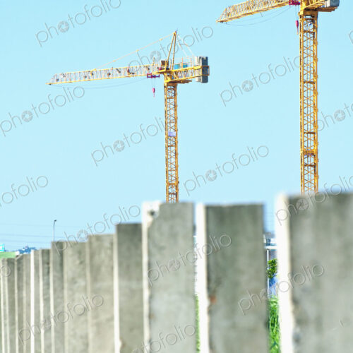 Two construction cranes above a row of concrete pillars