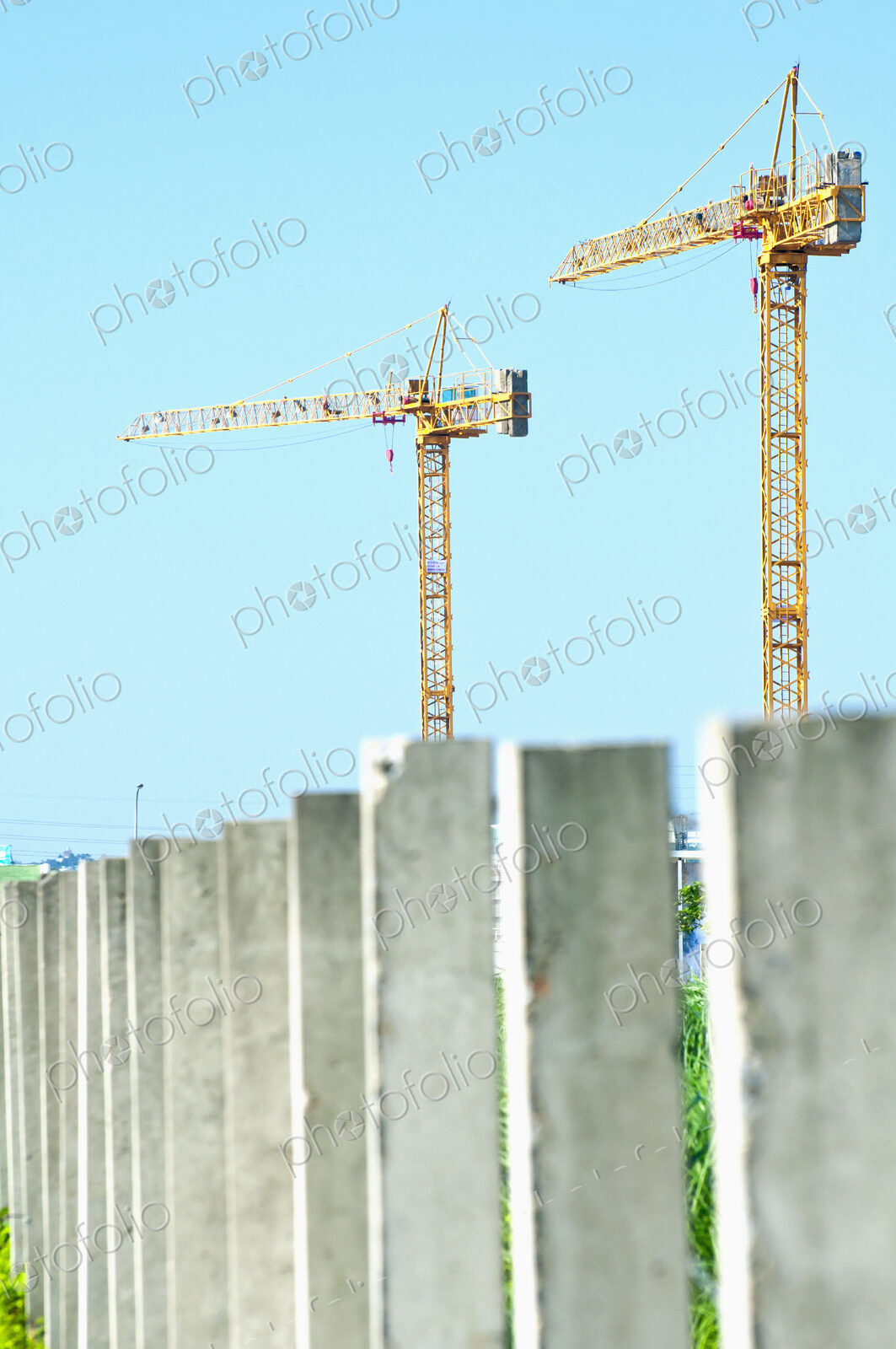 Two construction cranes above a row of concrete pillars