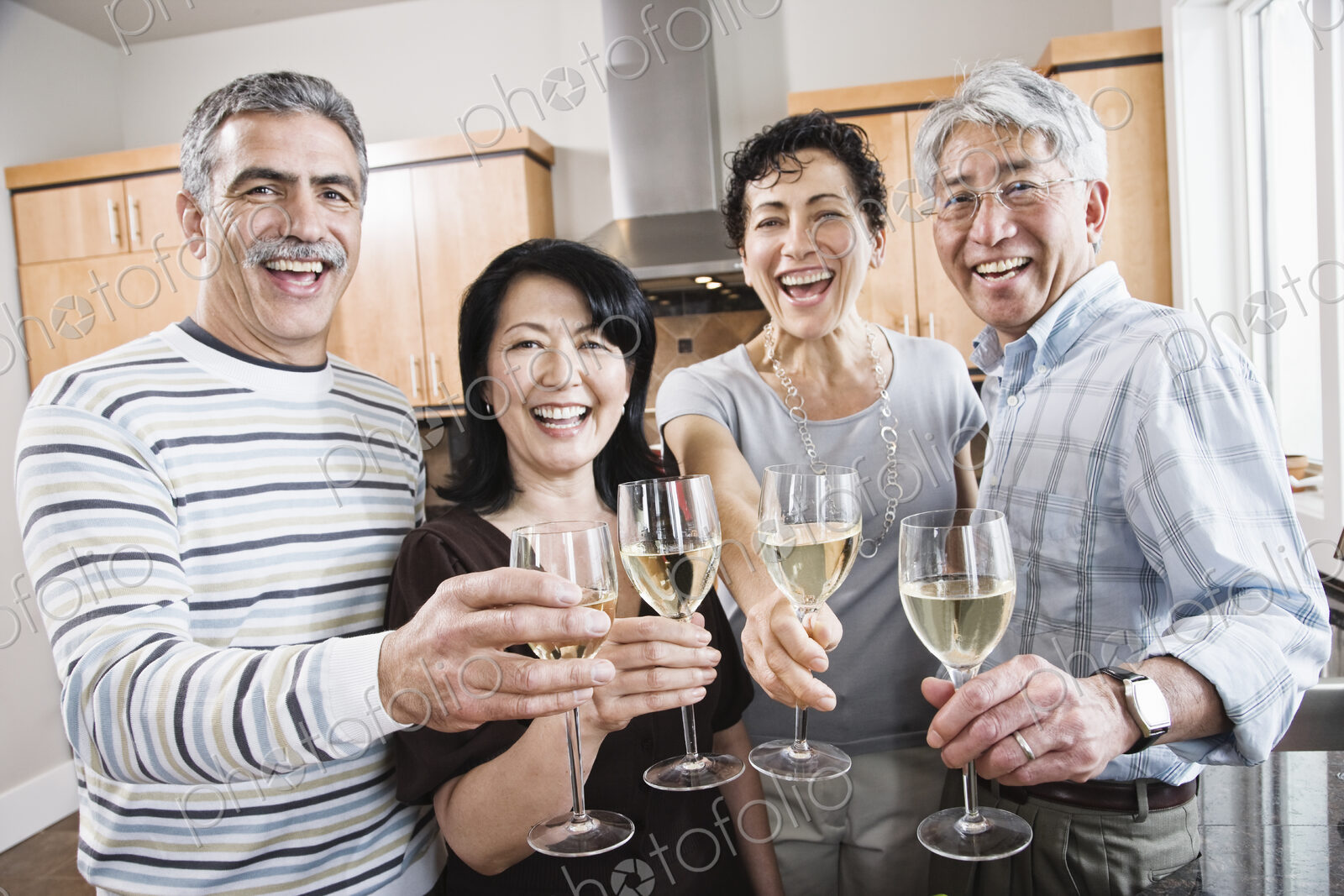 Two couples in a kitchen, Asian and Caucasian men and women making a toast with…