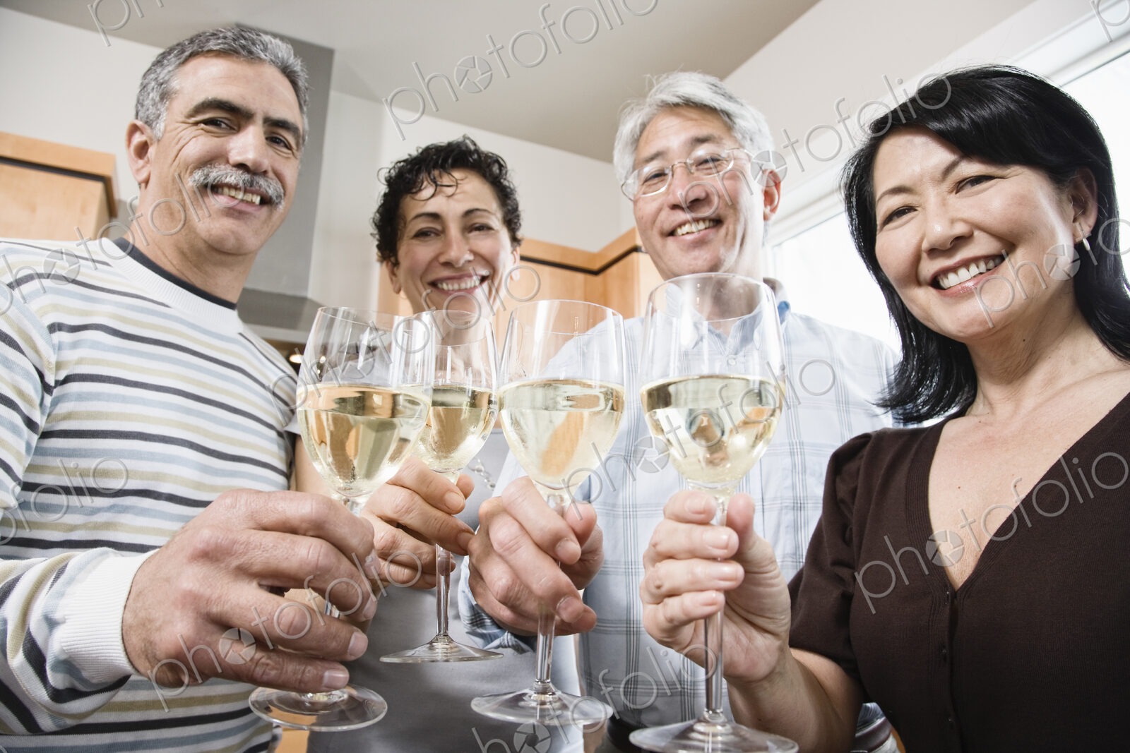 Two couples in a kitchen, Asian and Caucasian men and women making a toast with…
