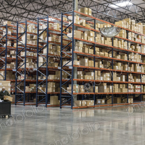 Two employees checking inventory in temporary storage in a distribution warehouse. Two employees checking inventory in temporary storage in a distribution warehouse.