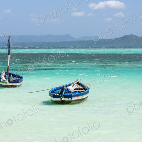 Two fishing boats moored in the shallows on a beach, turquoise sea and mountains. Two fishing boats moored in the shallows on a beach, turquoise sea and mountains.