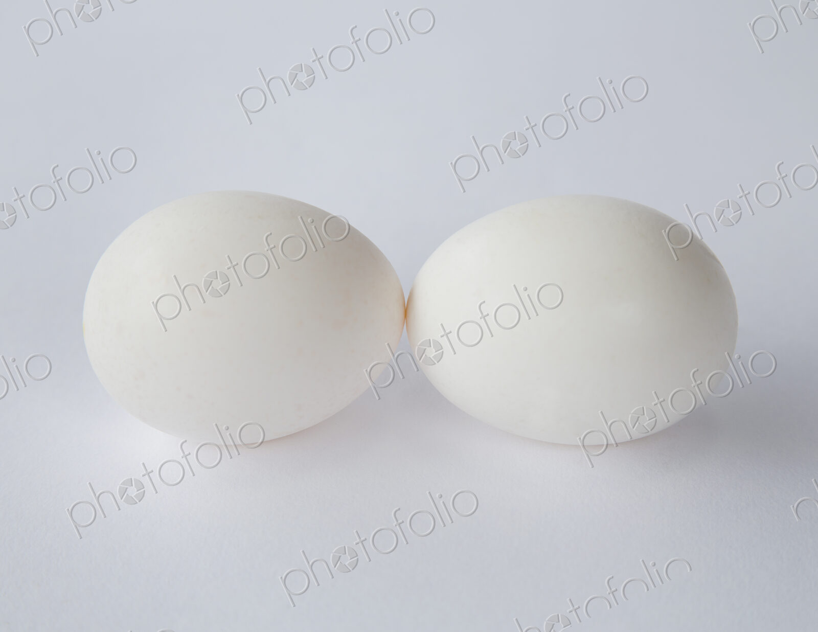 Two free range organic eggs with white shells, end to end, against a white background.