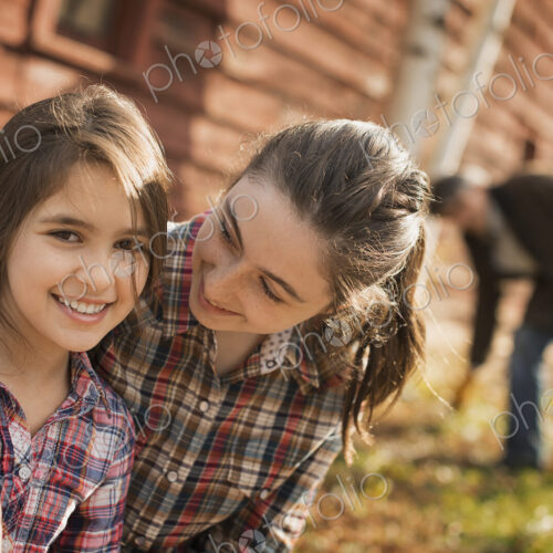 Two girls and a man outside a barn on an organic farm.
