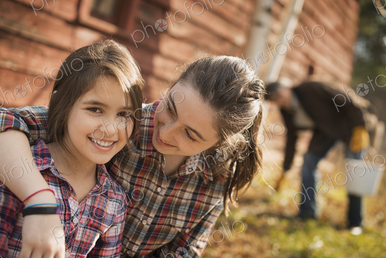Two girls and a man outside a barn on an organic farm.