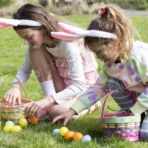 Two girls collecting Easter eggs in garden. Two girls collecting Easter eggs in garden.