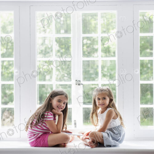 Two girls playing, sharing a digital tablet.