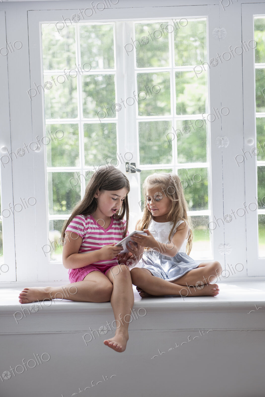 Two girls playing, sharing a digital tablet.