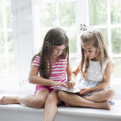 Two girls playing, sharing a digital tablet. Two girls playing, sharing a digital tablet.