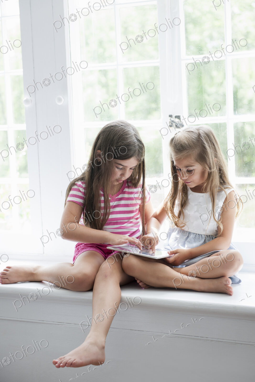Two girls playing, sharing a digital tablet.