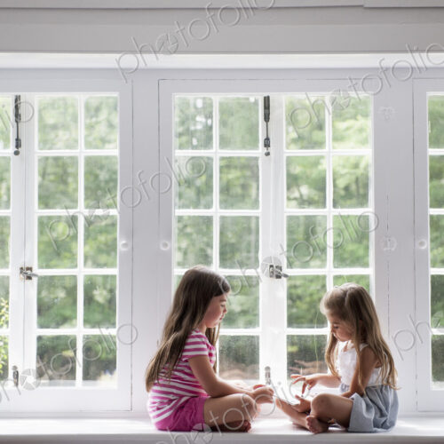 Two girls sitting indoors cross legged. Two girls sitting indoors cross legged.