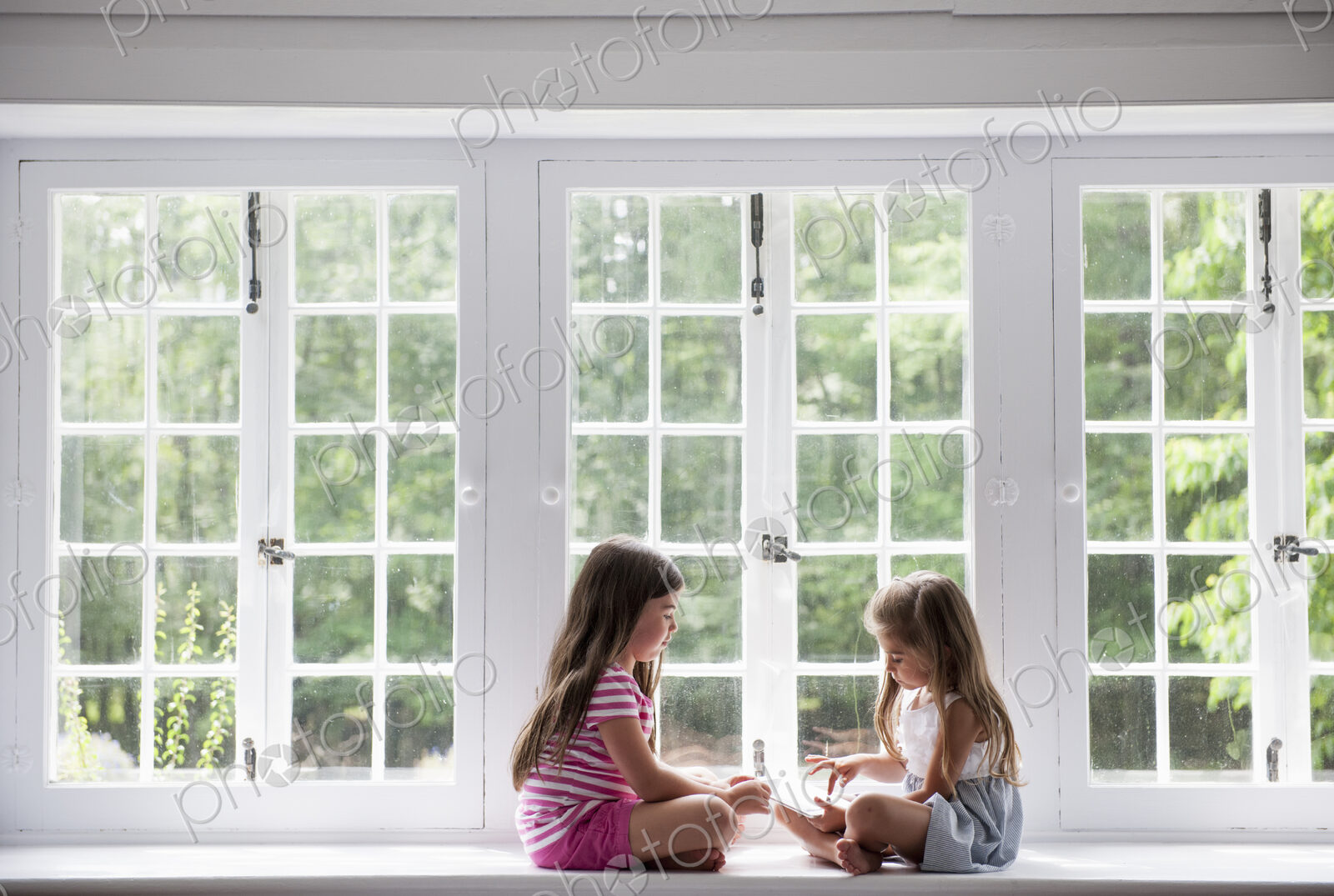 Two girls sitting indoors cross legged.