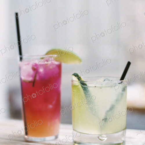Two glasses of chilled drinks, with straws and garnishes. Lemonade and iced tea. Two glasses of chilled drinks, with straws and garnishes. Lemonade and iced tea.