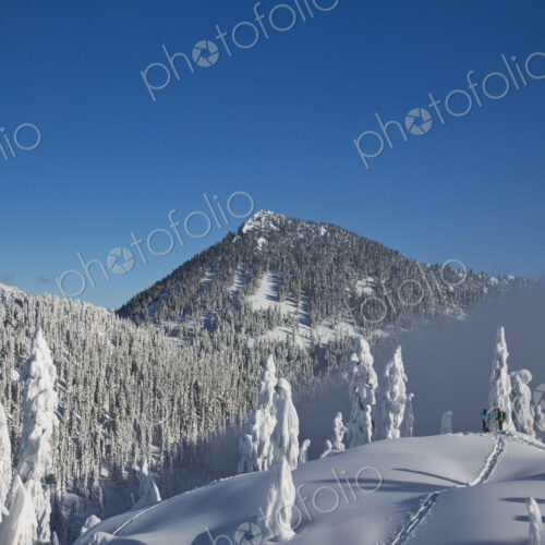 Two hikers enjoy a blue bird day in the middle of winter in the snow covered Cascade… Two hikers enjoy a blue bird day in the middle of winter in the snow covered Cascade…