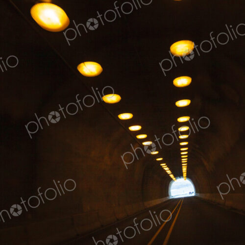 Two lane highway through a tunnel, view of the lights leading to the daylight and the… Two lane highway through a tunnel, view of the lights leading to the daylight and the…