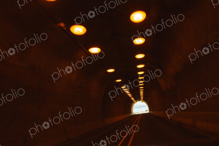 Two lane highway through a tunnel, view of the lights leading to the daylight and the…