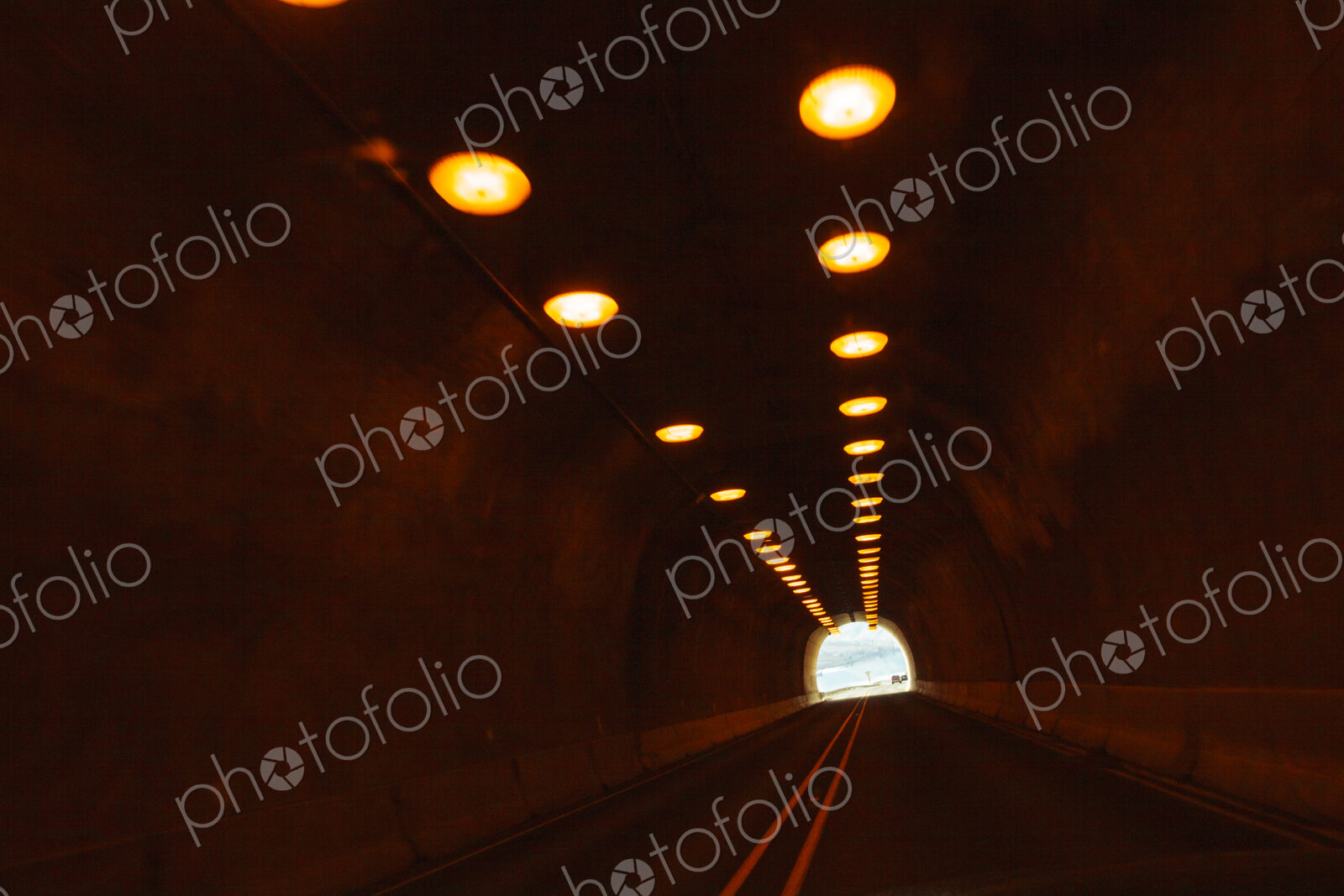 Two lane highway through a tunnel, view of the lights leading to the daylight and the…