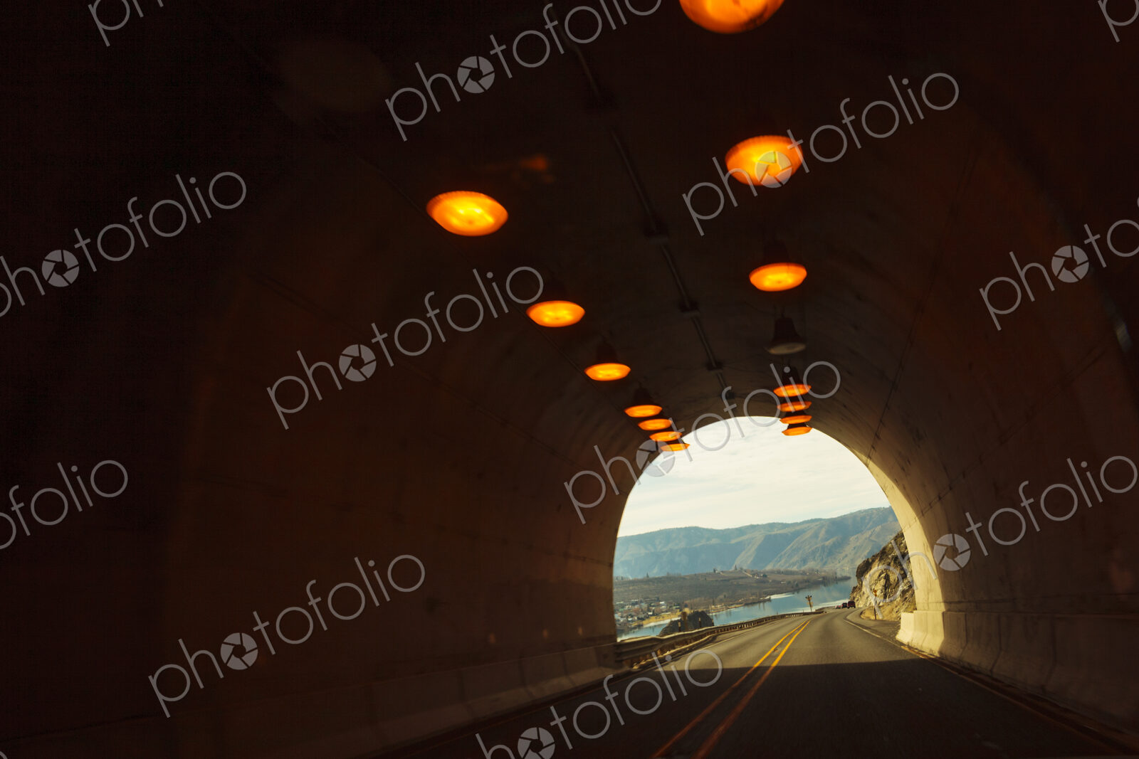 Two lane highway through a tunnel, view of the lights leading to the daylight and the…