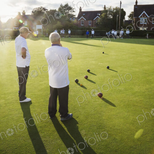 Two lawn bowls players, men standing discussing the game, and a clutch of lawn bowls… Two lawn bowls players, men standing discussing the game, and a clutch of lawn bowls…