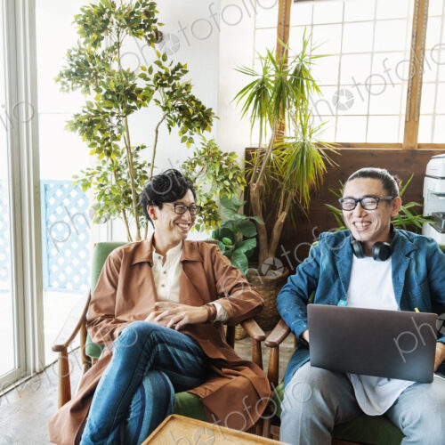 Two male Japanese professionals working on laptop computers in a co-working space. Two male Japanese professionals working on laptop computers in a co-working space.