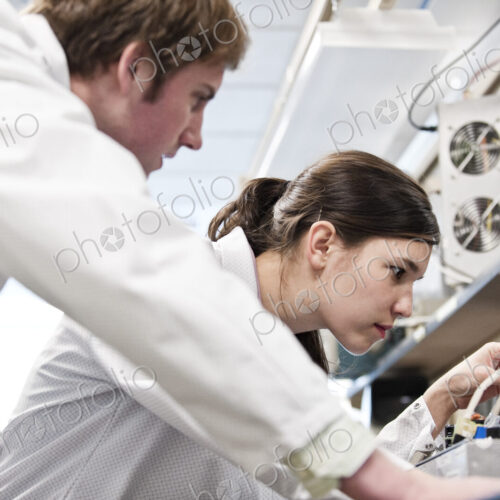 Two male and female technicians in white coats working together, research and development Two male and female technicians in white coats working together, research and development