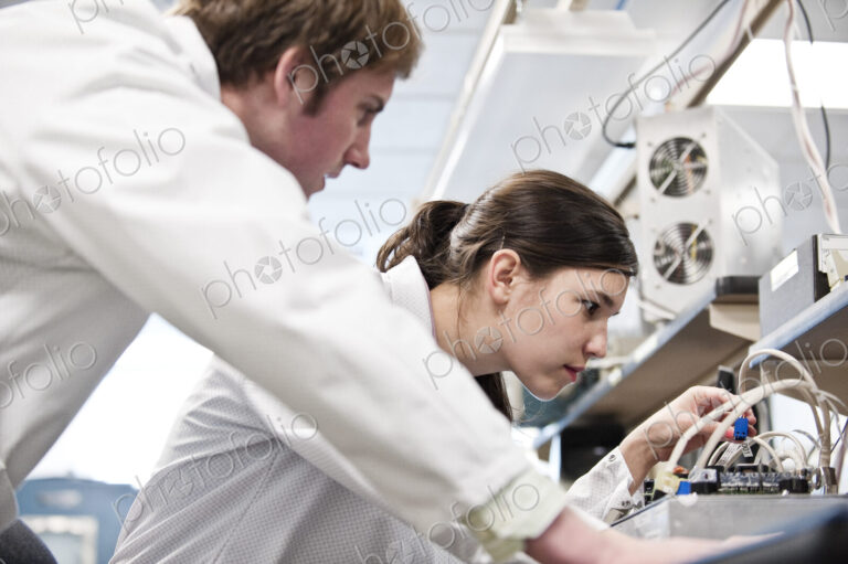 Two male and female technicians in white coats working together, research and development