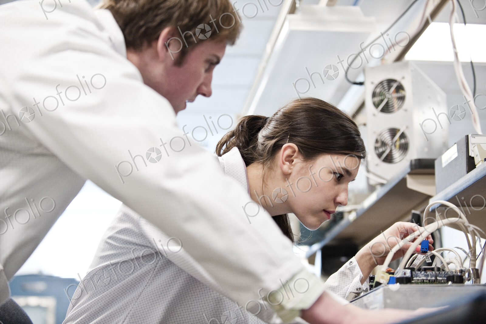 Two male and female technicians in white coats working together, research and development