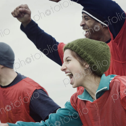 Two men and one woman, friends cheering on their team at a winter sporting event. Two men and one woman, friends cheering on their team at a winter sporting event.
