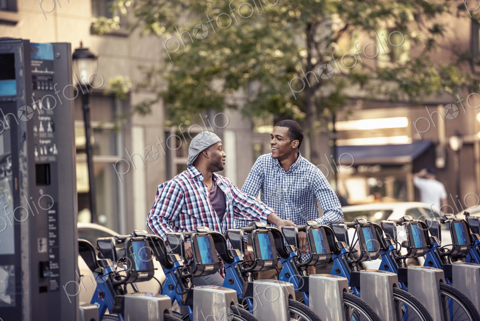 Two men by a rack of bicycles for hire in a city park