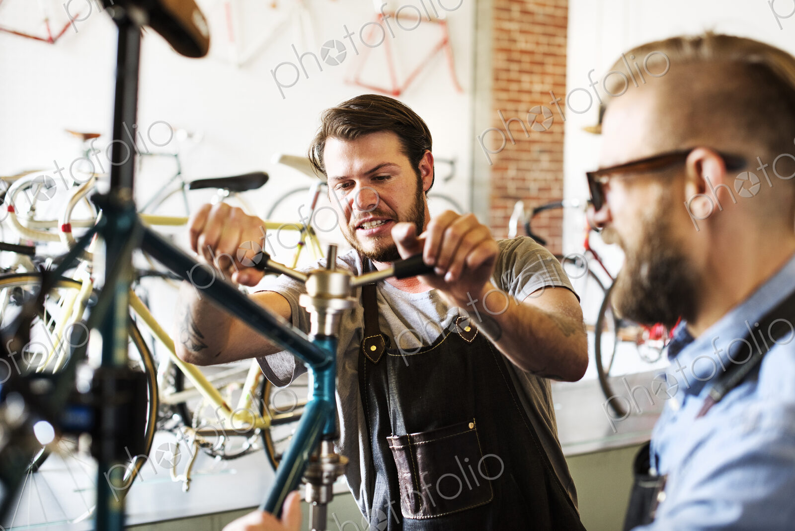 Two men in a cycle repair shop, looking at a bicycle.