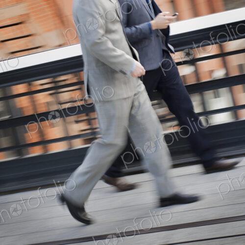 Two men in business clothes walking along a city sidewalk.
