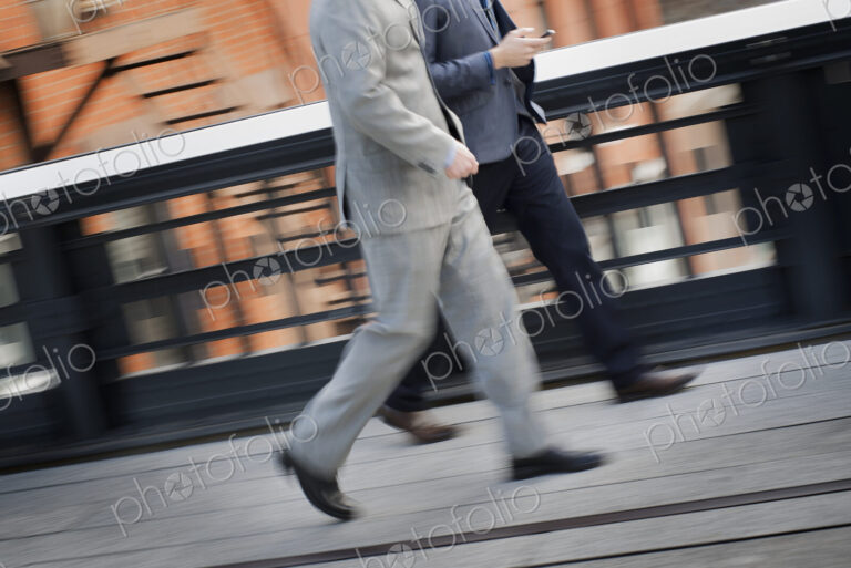 Two men in business clothes walking along a city sidewalk.