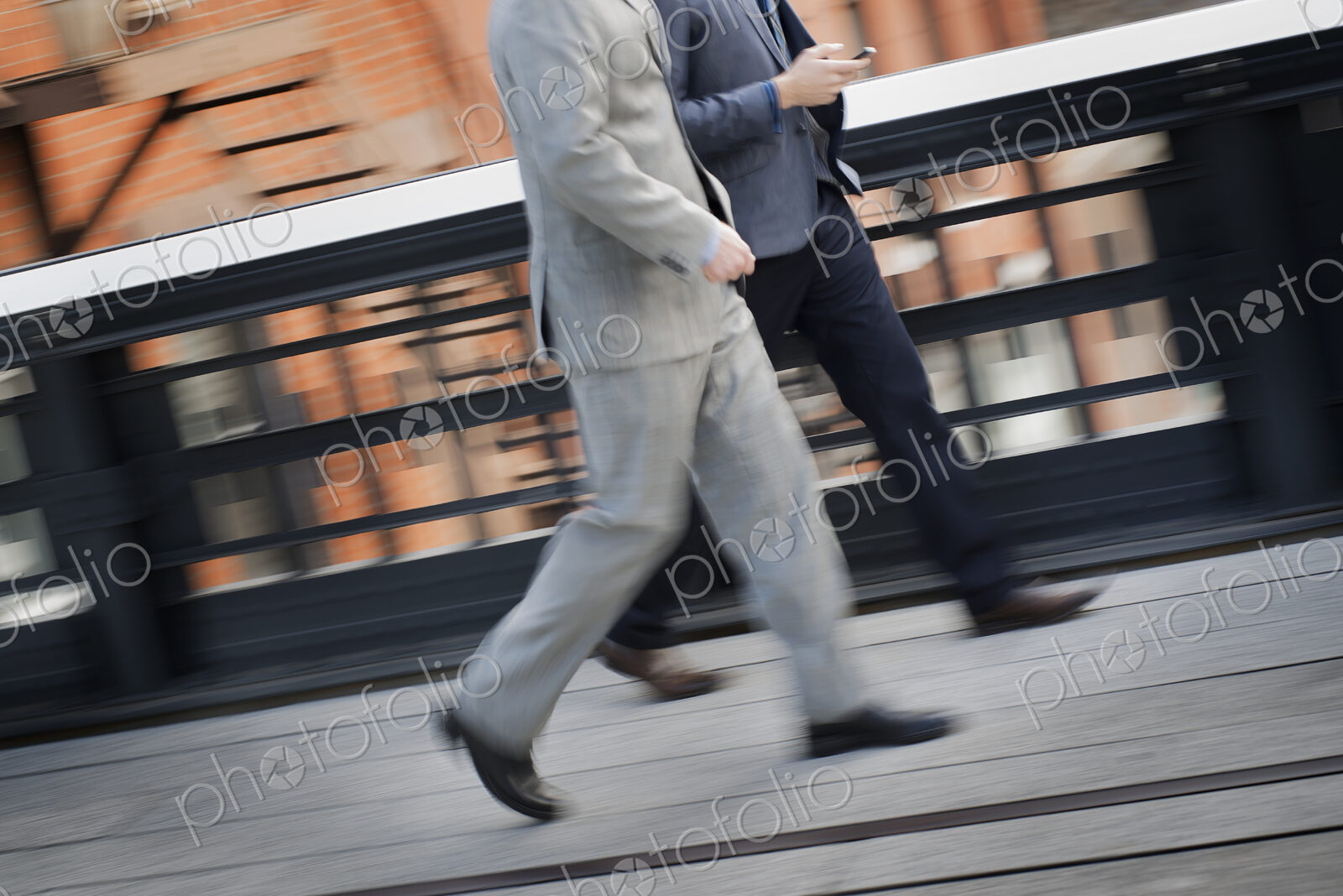 Two men in business clothes walking along a city sidewalk.