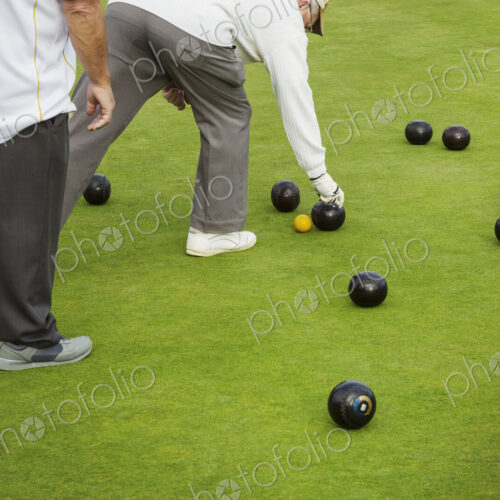 Two men on a bowls green, lawn bowls players, one bending down to pick up a wooden… Two men on a bowls green, lawn bowls players, one bending down to pick up a wooden…