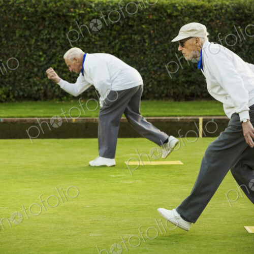 Two men preparing to deliver a lawn bowl shot, bending down and swinging their arms. Two men preparing to deliver a lawn bowl shot, bending down and swinging their arms.