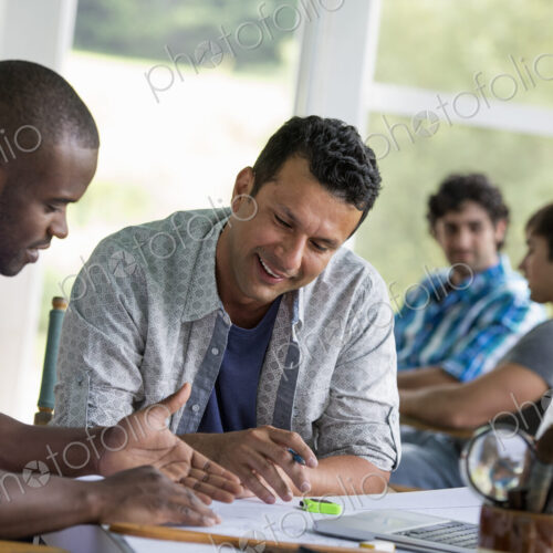Two men seated, working together. Two men seated, working together.