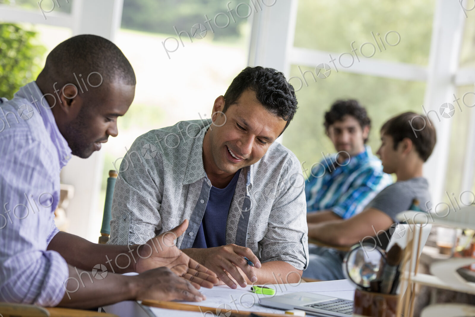 Two men seated, working together.