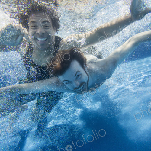 Two men swimming under water in a swimming pool. Two men swimming under water in a swimming pool.
