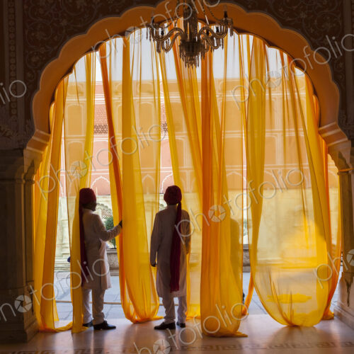 Two men under arch decorated with translucent orange curtains. Two men under arch decorated with translucent orange curtains.