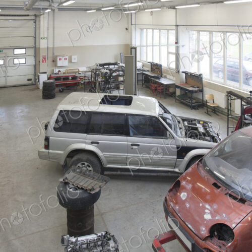 Two mini vans in a large repair workshop or garage.