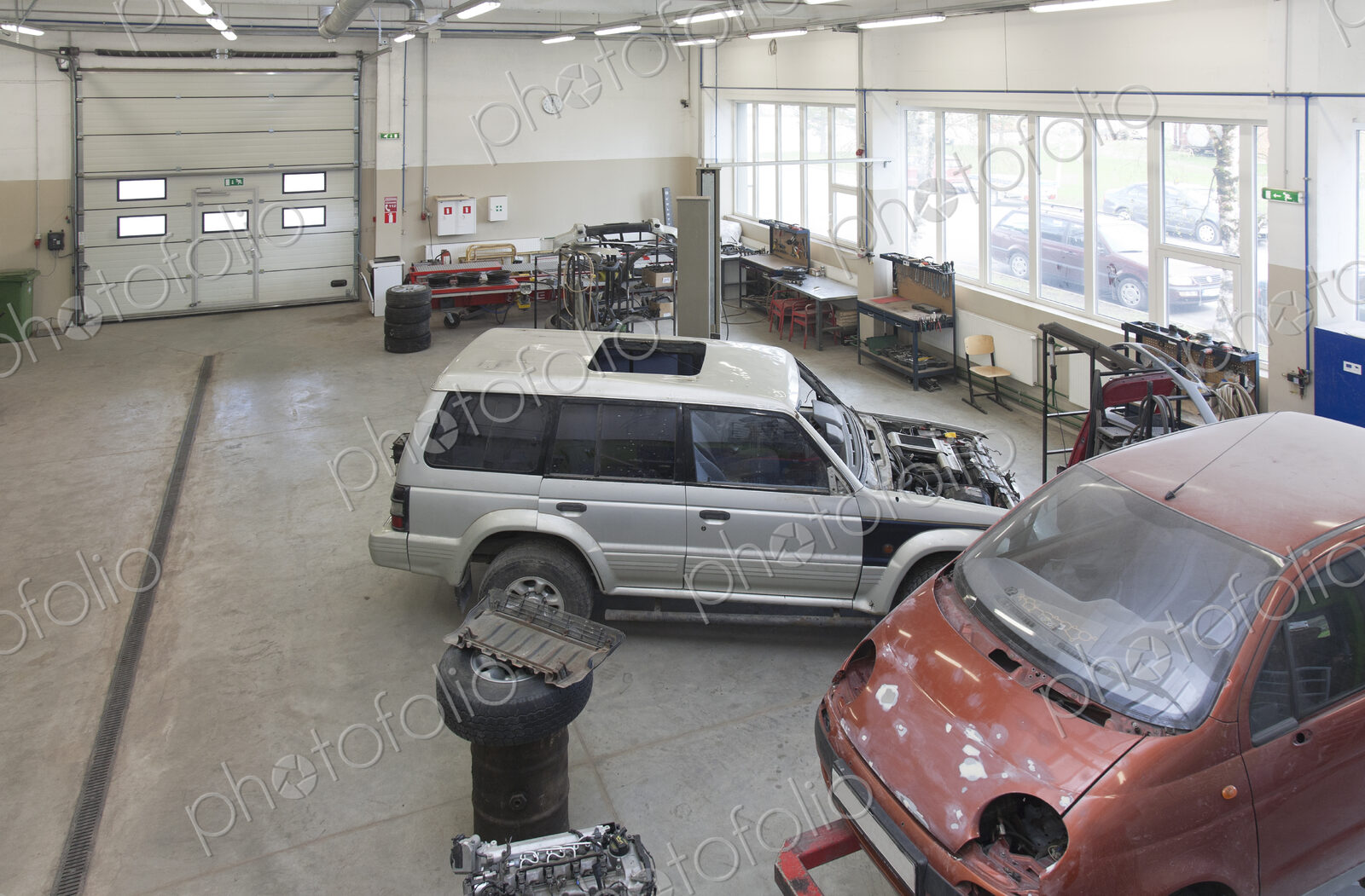 Two mini vans in a large repair workshop or garage.