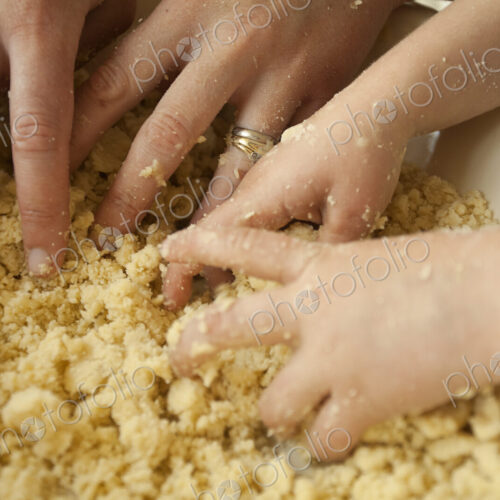 Two pairs of hands mixing ingredients in a bowl, an adult and a child cooking together. Two pairs of hands mixing ingredients in a bowl, an adult and a child cooking together.